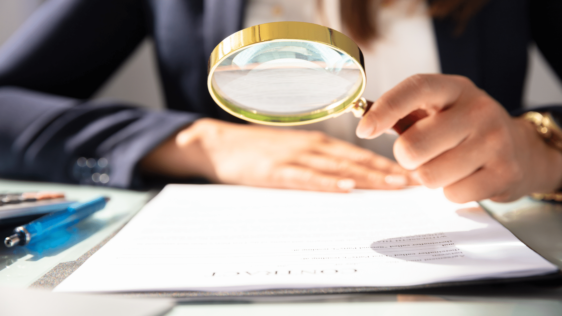 Person examining document with magnifying glass